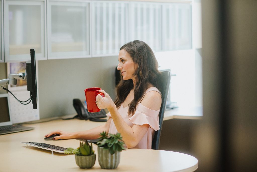 Our Office Solutions employee is enjoying a cup of coffee while working.